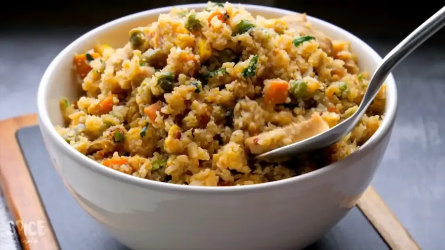 15 Minutes of Cauliflower Fried Rice with chicken is on a serving bowl with a spoon