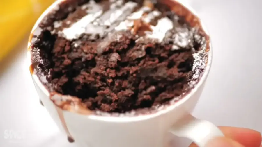 1 Minute Perfect Chocolate Mug Cake topping with chocolate sauce and powdered sugar