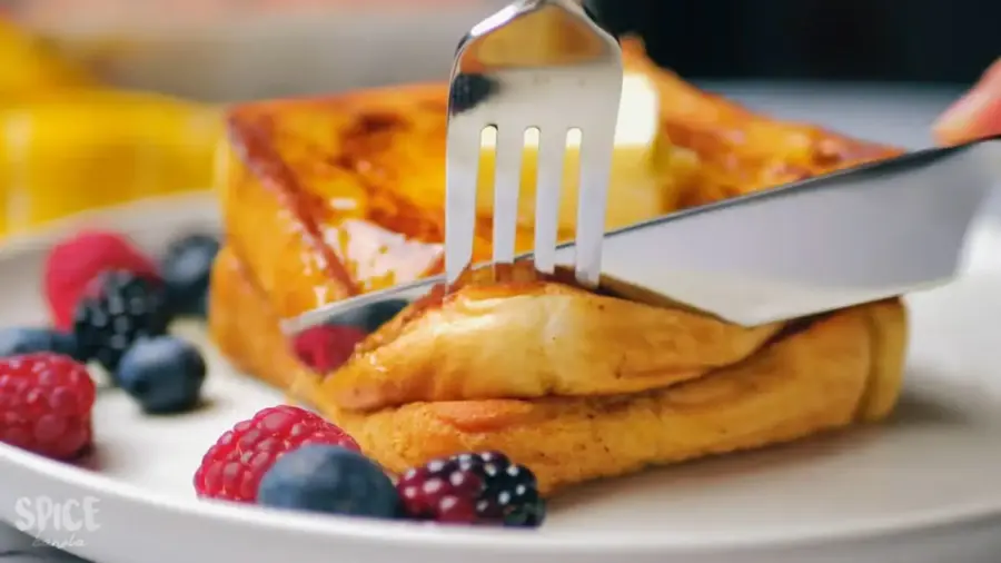 Classic French Toast For Breakfast on a serving plate with some berries, butter, and honey