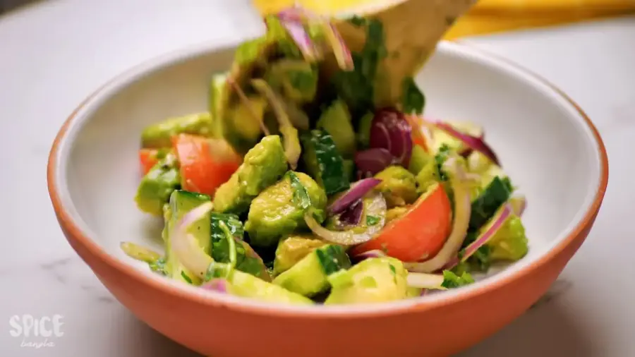 Cucumber Tomato And Avocado Salad in a large mixing bowl with a spatula