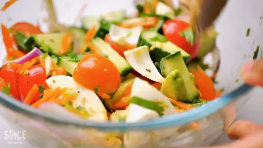 egg salad recipe with tomato, cucumber, and avocado in a large mixing bowl