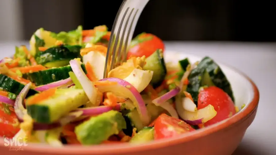 egg salad recipe with tomato, avocado, and cucumber in a serving bowl with a fork