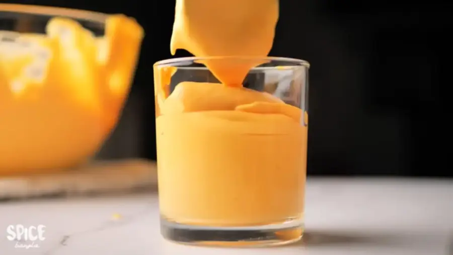 Mango Mousse serving in a glass with a spoon
