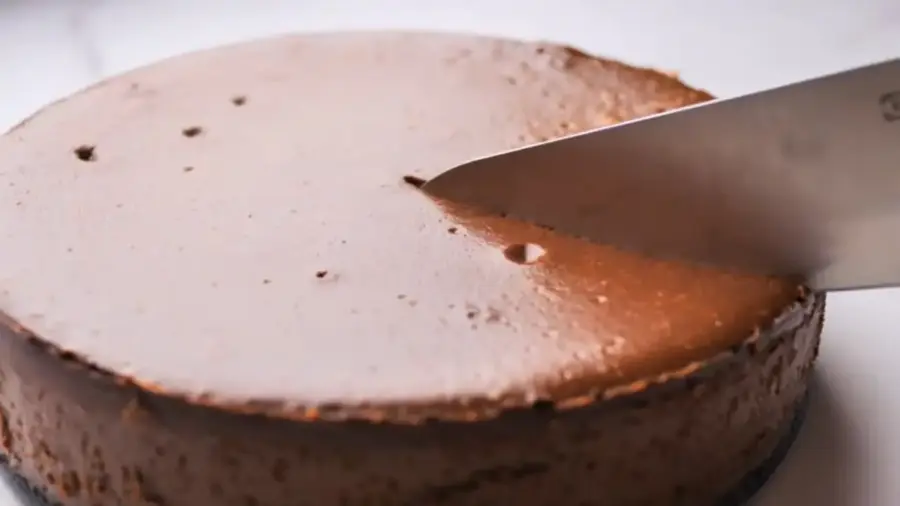 The Ultimate Chocolate Cheesecake Recipe cutting by a knife