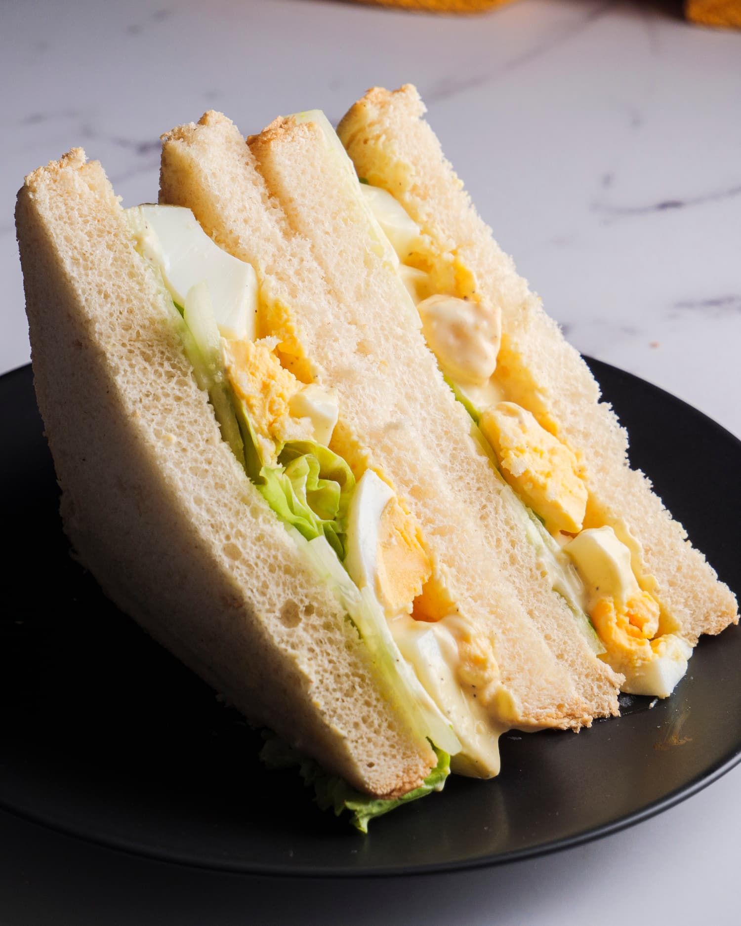 2 pieces of egg salad sandwich on a serving plate