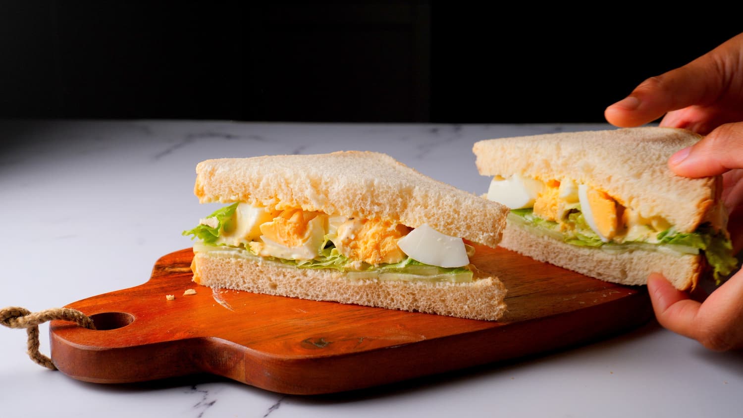 stakes of egg salad sandwich on a chopping board