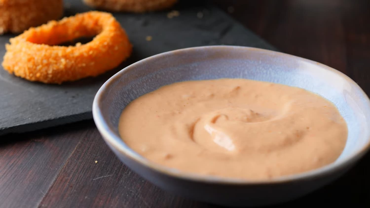 crispy onion ring on a serving plate with dipping sauce