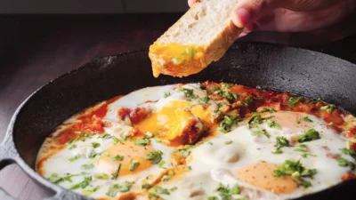 Shakshuka recipe on a pan with a piece of bread