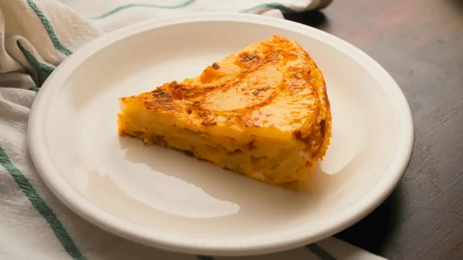 tortilla de patatas or Spanish omelette on a serving plate with a knife