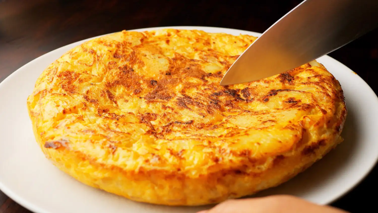 tortilla de patatas on a serving plate with a knife