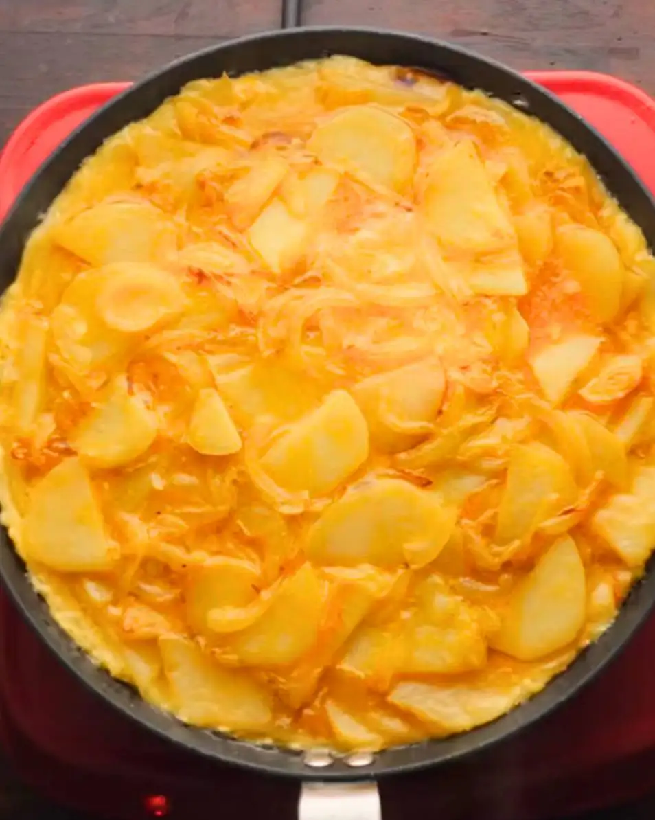 tortilla de patatas or Spanish omelette cooking on a pan