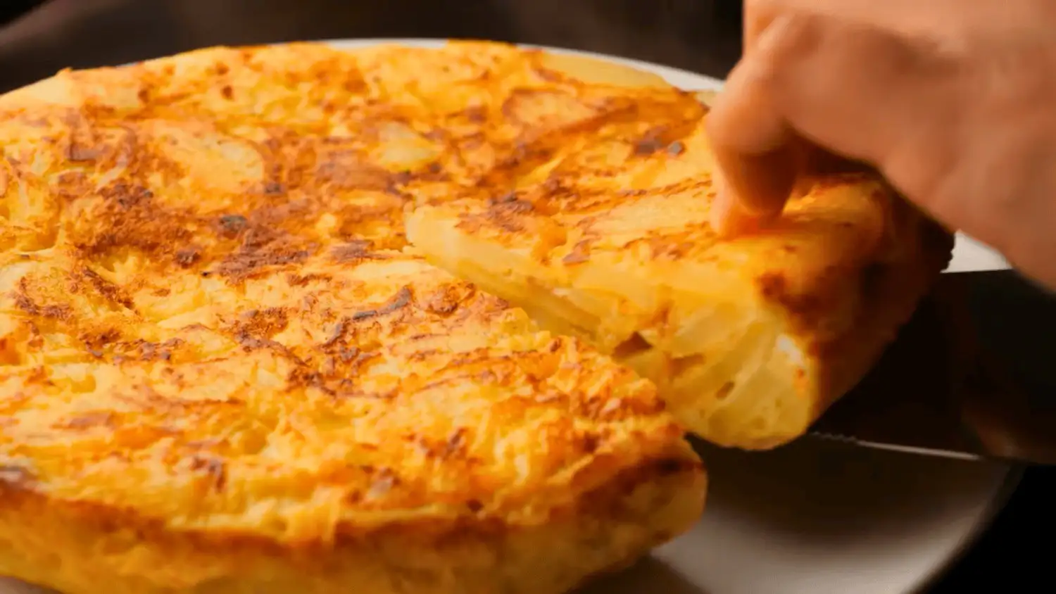 tortilla de patatas or Spanish omelette on a serving plate with a knife