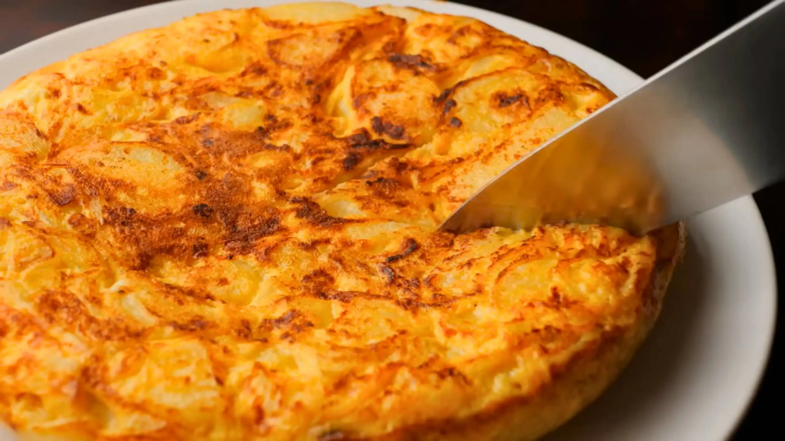 tortilla de patatas or Spanish omelette on a serving plate with a knife