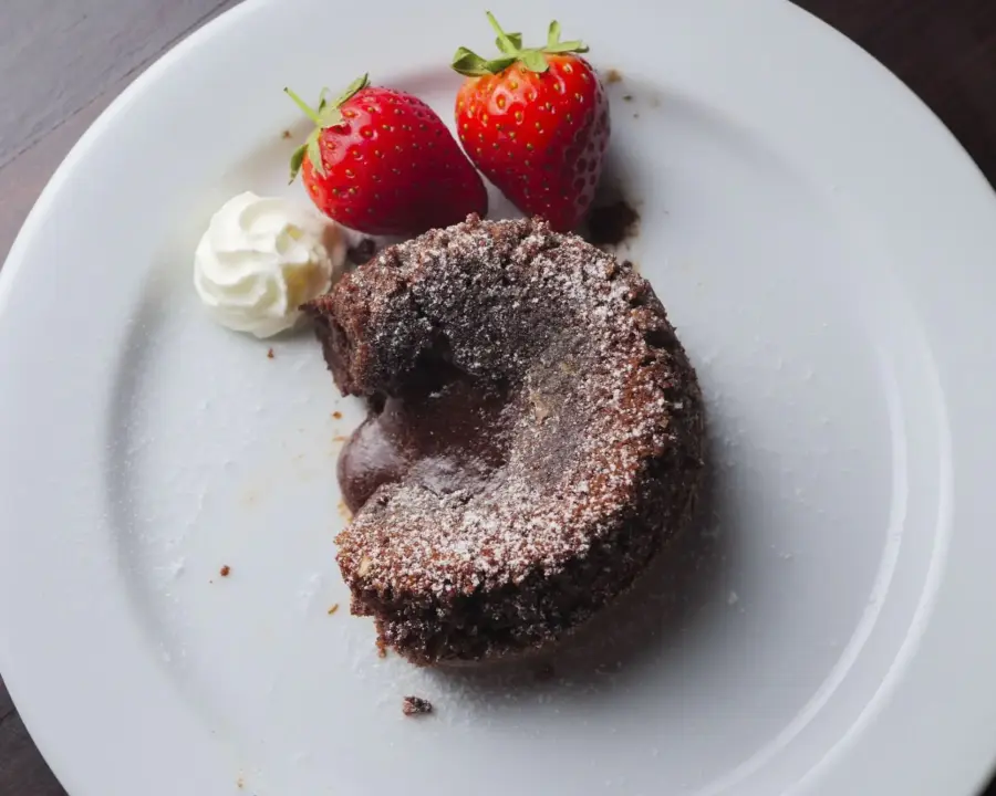 Chocolate Lava Cake recipe on a serving plate with a dolop of whipped cream and strawberry
