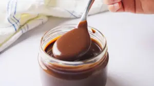 Hot Fudge Sauce in a messon jar with a spoon