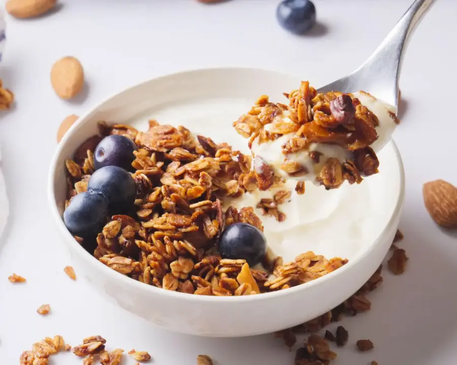 Vanilla Almond Granola in a serving bowl with yogurt, berries and a spoon