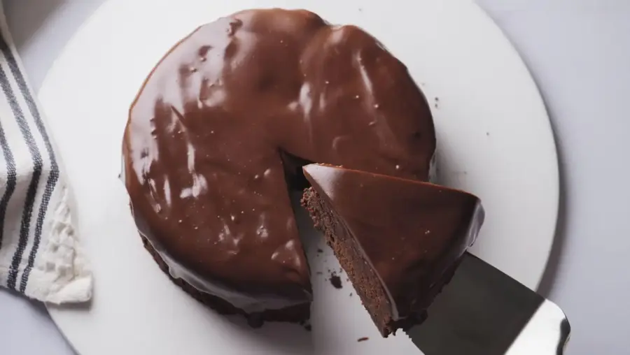 Brownie Cake on a cake serving plate with a slice on a knife