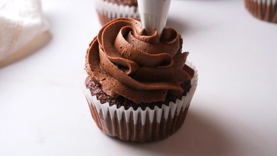 Chocolate Cupcake on a serving surface with buttercream frosting in piping