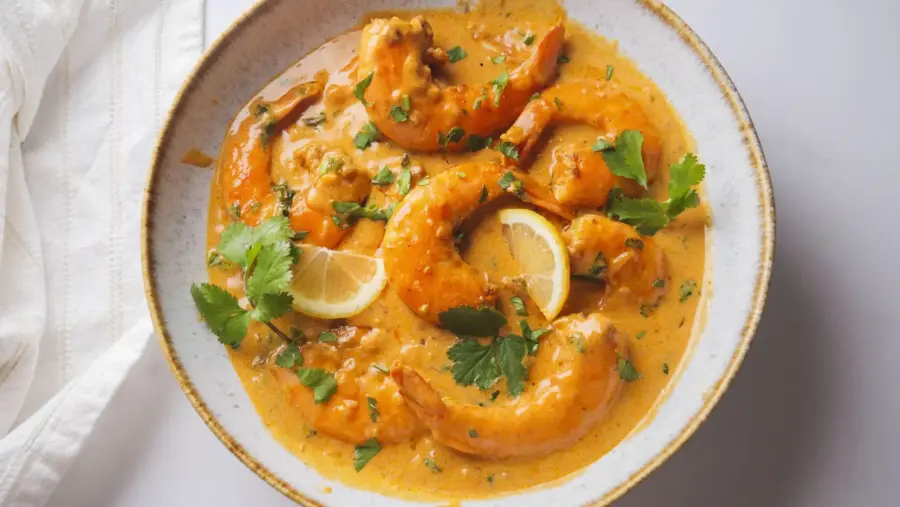 Creamy Coconut Shrimp in a serving bowl with lemon in it